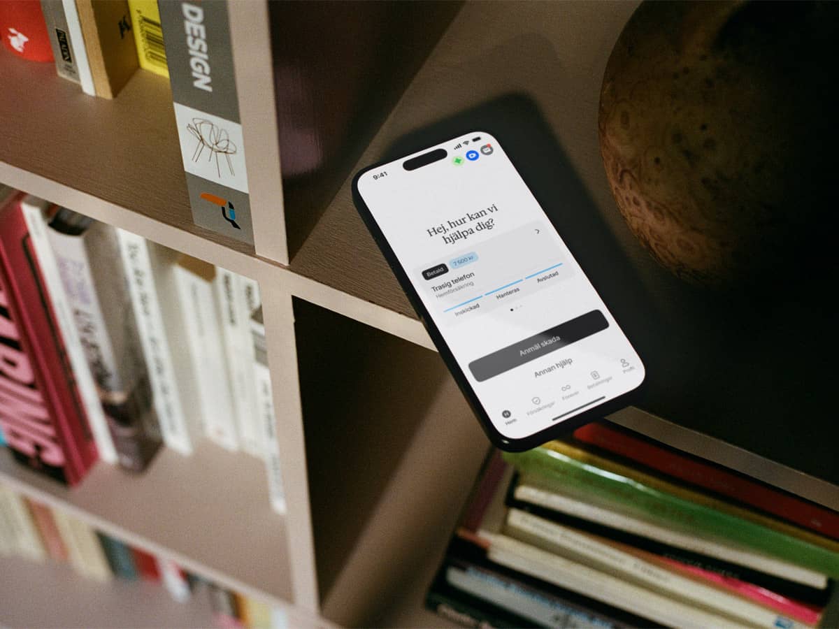 Mobiltelefon med Hedvig-appen öppen ligger i en bokhylla
