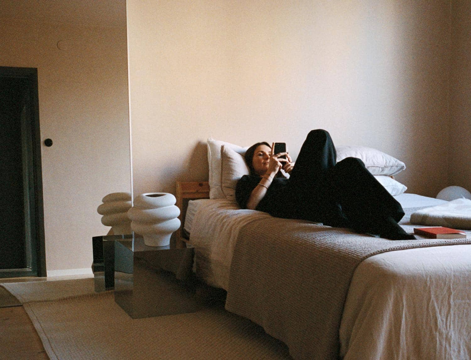 En person ligger och kollar på telefonen i sin lägenhet