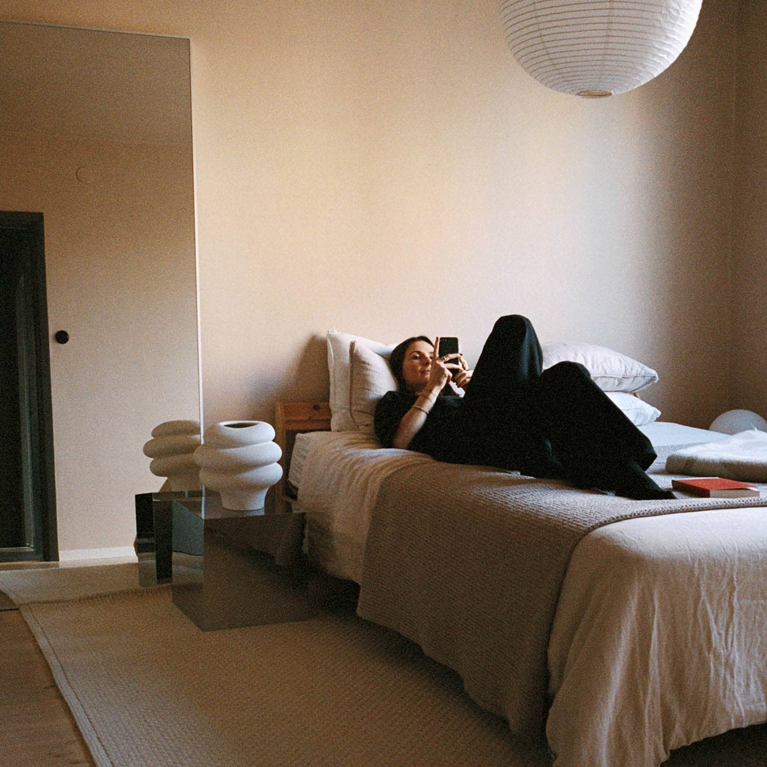 En person ligger och kollar på telefonen i sin lägenhet